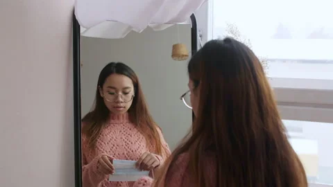 Middle Eastern young female puts on a protective face mask before leaving her 库存影片 149005702