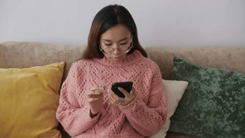 Middle Eastern young female sitting on the sofa in the living room with a 動画素材 149770061