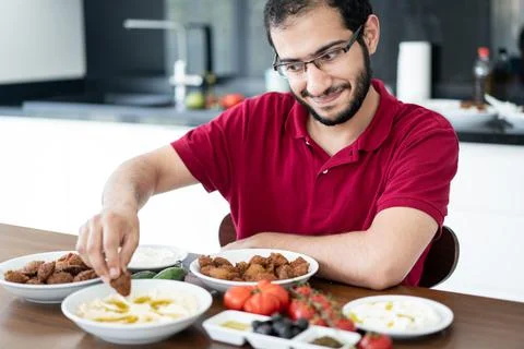 Middle Eastern young man sitting and eating traditional food Stock Photos