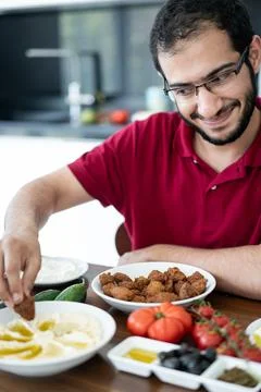 Middle Eastern young man sitting and eating traditional food Stock Photos