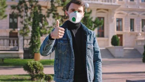 In the middle of empty street man with a protective mask suggesting to people to Stock Photos