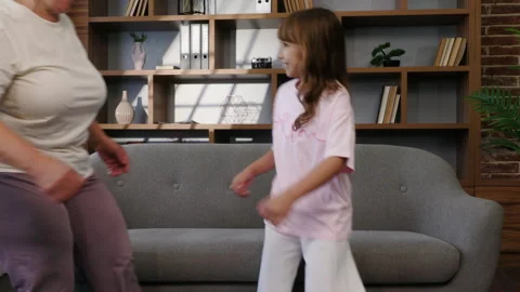 In the middle of a living room, there is a sofa. A grandmother and granddaughter Stock Footage 281968341