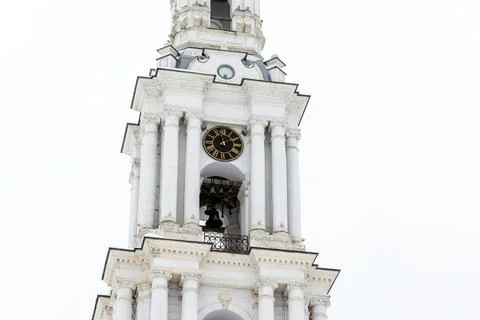 Middle part with tower clock of a white bell tower rises under overcast win.. Stock Photos