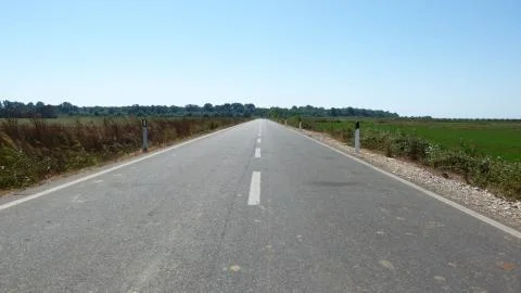 In the middle of a paved and lined road that goes towards the horizon Stock Photos