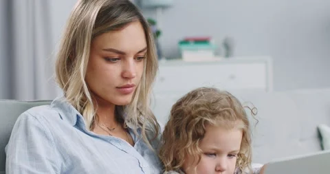Middle plan of concentrated mum and daughter having fun using learning laptop at Stock Footage 132320616