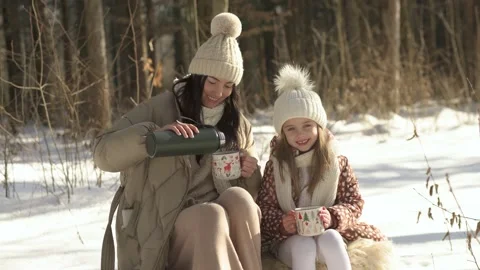 Middle plan. Mom pours warm tea to her daughter from a thermos. Stock Footage 154205824
