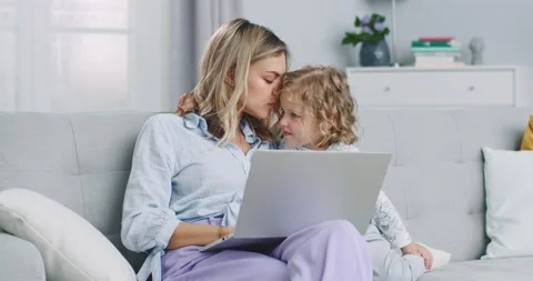 Middle plan of mother multitasking using laptop computer at home with her baby Stock Footage 132320591