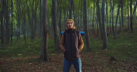 Middle plan of young man standing in forest snaping zipper on sports jacket and Stock Footage 154172293
