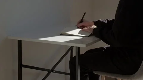 Middle realtime shot: man sitting at the table and writing text in the diary Stock Footage 229896717