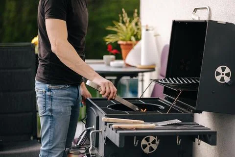 Middle selection of handsome man make a fire and controls the process. BBQ grill Stock Photos