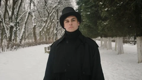 Middle view shot: A man in a black cloak and hat walks in the park alley. 60fps Vídeo Stock 102192007