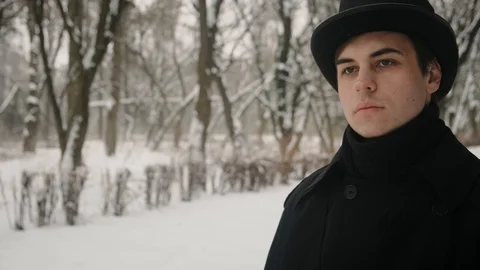 Middle view shot: A man in a black cloak and hat walks in the park alley. 60fps Stockbeeldmateriaal 102192211