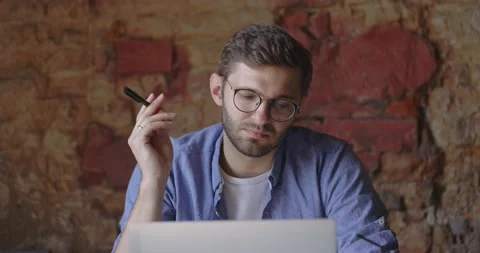 A middle view of thoughtful serious man in eyeglass sit with laptop thinking of Stock Footage 164674791
