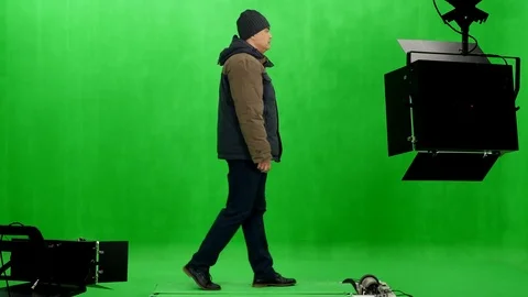 Middle years man in winter jacket and hat walks in chroma key studio Stock Footage