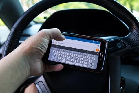 Middletown, CT USA. Jun 2 2016. Drivers hand holding smartphone and texting d Stock Photos