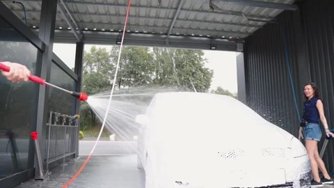Midframe carwash action inside covered tunnel with spraying water and smiling Stock Footage 340920878