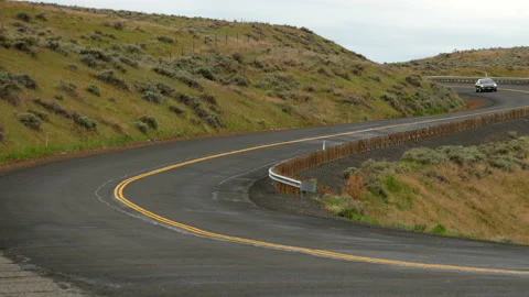 A midnight metalic gray 2018 Tesla Model 3 drives on winding country road. Stock Footage 132123733