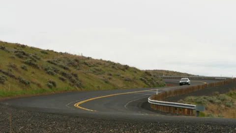 A midnight metalic gray 2019 Tesla Model 3 drives on winding country road. Video stock 132123749