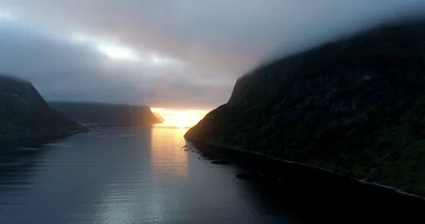 Midnight sun under thick clouds shinning on fjord. 스톡 동영상 113285992