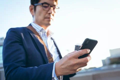 Midsection of asian businessman using smartphone in city street Fotos Stock