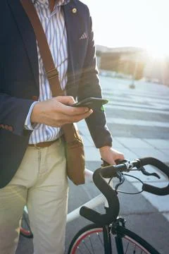 Midsection of asian businessman using smartphone holding bike in city street 写真素材