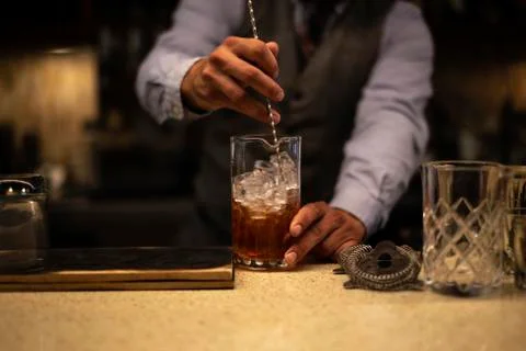 Midsection of bartender mixing drink while standing at bar counter Photos