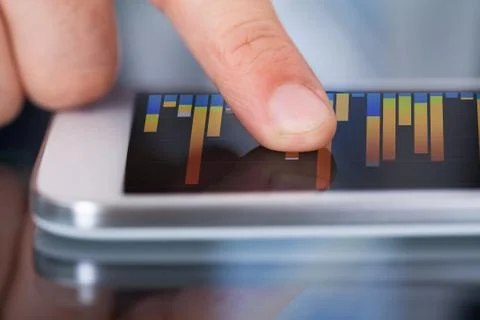 Midsection of businessman comparing graphs on digital tablet at desk in offic Stock Photos