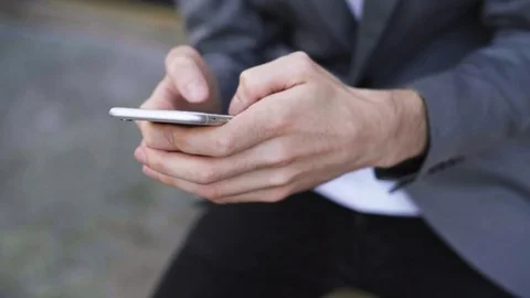 Midsection of businessman text messaging through smart phone while sitting on Stock Footage