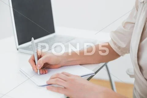 Midsection of a businesswoman writing notes by laptop Stock Photos
