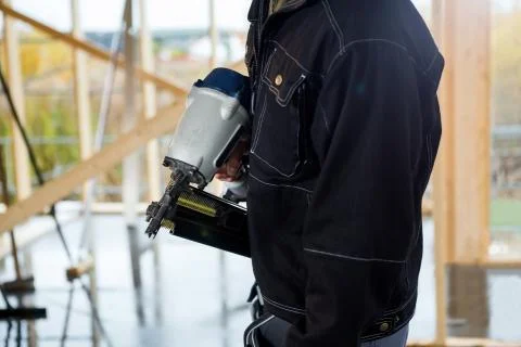 Midsection Of Carpenter Holding Drill Machine At Site Stock Photos