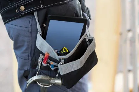 Midsection Of Carpenter With Tablet Computer And Tools In Bag Фото