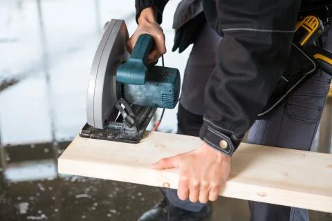 Midsection Of Carpenter Using Electric Saw To Cut Wood Stock Photos