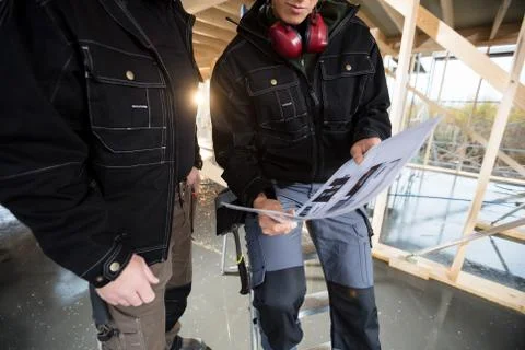 Midsection Of Carpenters With Plan At Site Foto stock