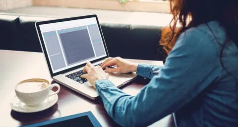Midsection of caucasian female programmer sitting with coffee, using laptop with 写真素材