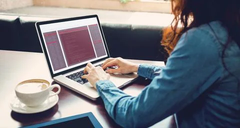 Midsection of caucasian female programmer sitting with coffee, using laptop with 写真素材