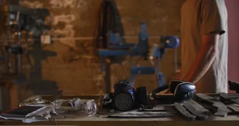Midsection of caucasian male blacksmith walking in workshop with tools on table Stock Footage 337536546