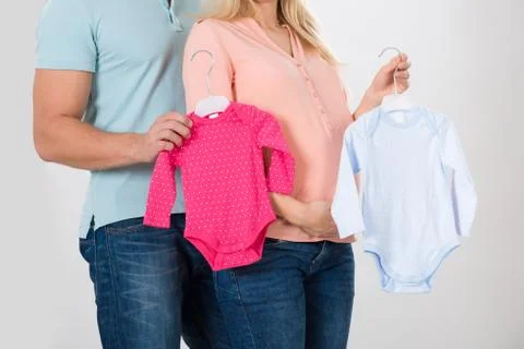 Midsection of couple holding baby clothing over white background Fotos Stock
