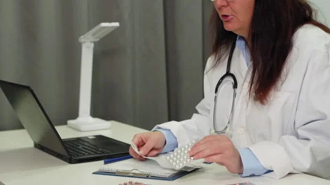 Midsection of female practitioner examining pills on table in clinic Stock Footage 263280607