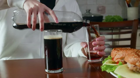 Midsection of girl serving cola drink in glass during meal at table Stock Footage 290188695
