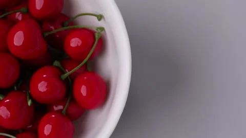 Midsection high angle shot of a bowl of cherries on white table Stock Footage 272563373