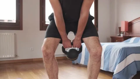 Midsection of man doing kettlebell swings while training at home. Stock Footage 158487929