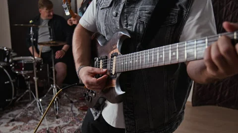 Midsection of Man Plugging Cable into Electric Guitar during Band Rehearsal Stock Footage 347122831