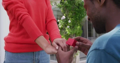 Midsection of man proposing to woman on knees with box with ring Stock Footage 340609692