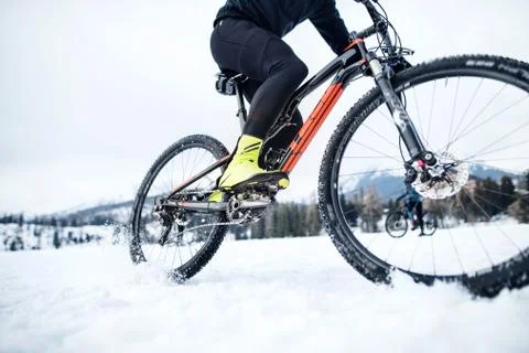 Midsection of mountain biker riding in snow outdoors in winter. Stock Photos
