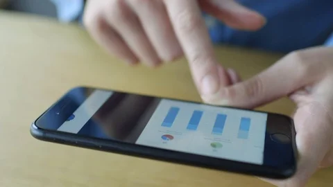 Midsection pan of woman scrolling through graphs on smart phone Stock Footage 70176352