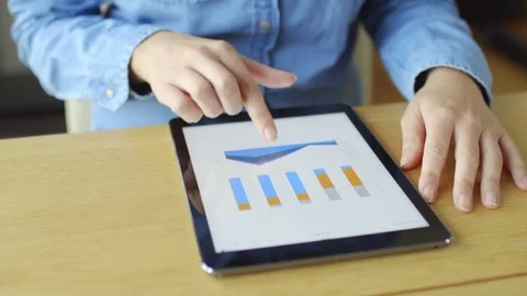 Midsection pan of woman scrolling through graphs on digital tablet Stock Footage 70181920