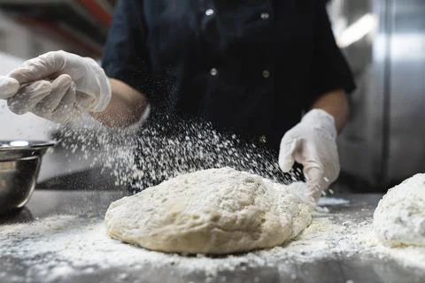 Midsection of professional chef preapring dough wearing sanitary gloves Фото