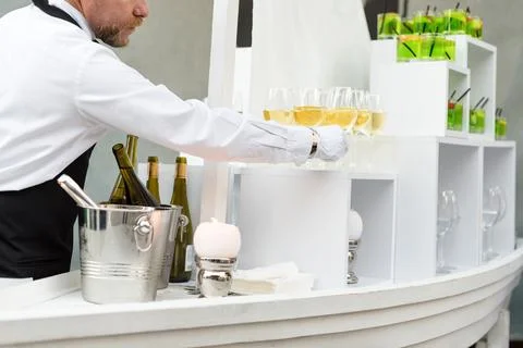 Midsection of professional waiter in uniform serving wine during buffet cater Stock Photos