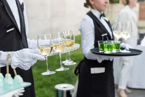 Midsection of professional waiters in uniform serving wine and snacks during  Stock Photos