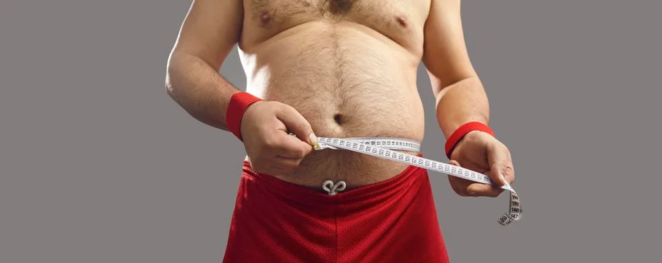 Midsection shot of an overweight man measuring his chubby waist with a tape Stock Photos